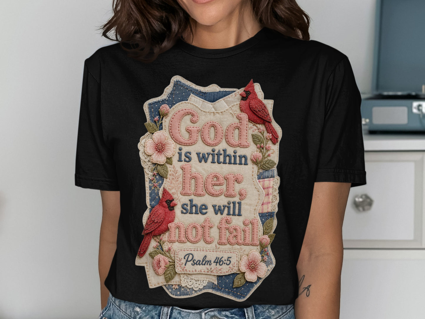 Black t-shirt with floral design and text "God is within her she will not fail Psalm 46:5".