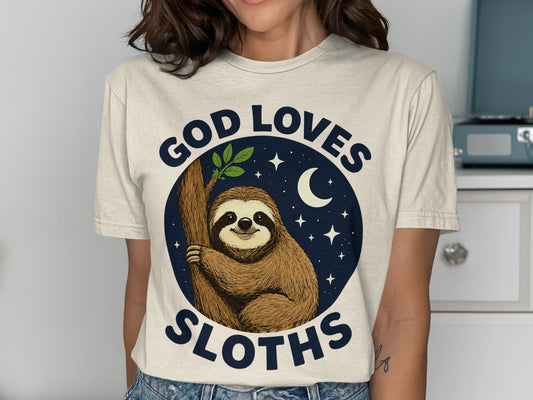 T-shirt graphic: Sloth on tree branch, "God Loves Sloths" text, night sky with moon and stars.