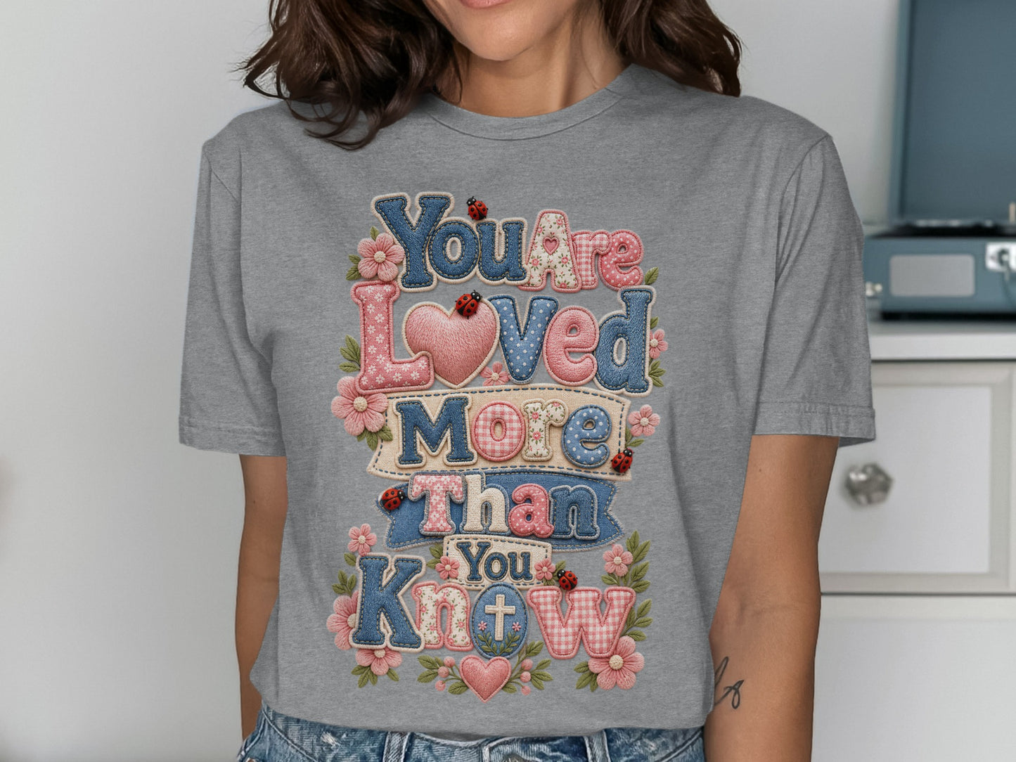 Grey t-shirt with "You Are Loved More Than You Know" text and floral accents.
