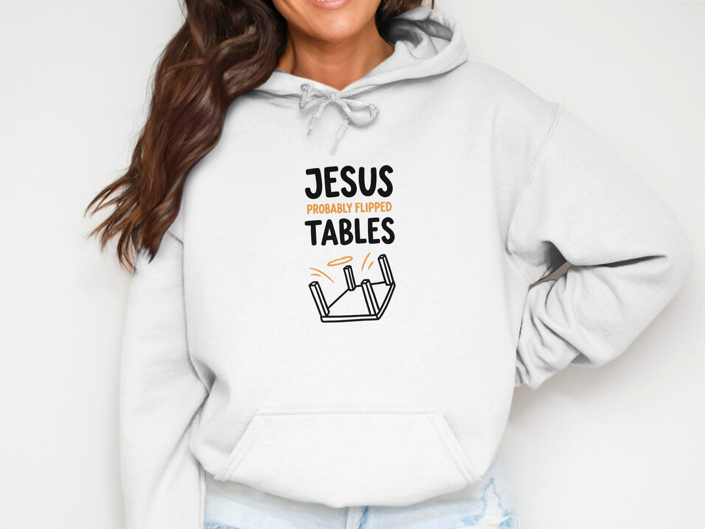 White hoodie with "Jesus probably flipped tables" text and overturned table graphic.