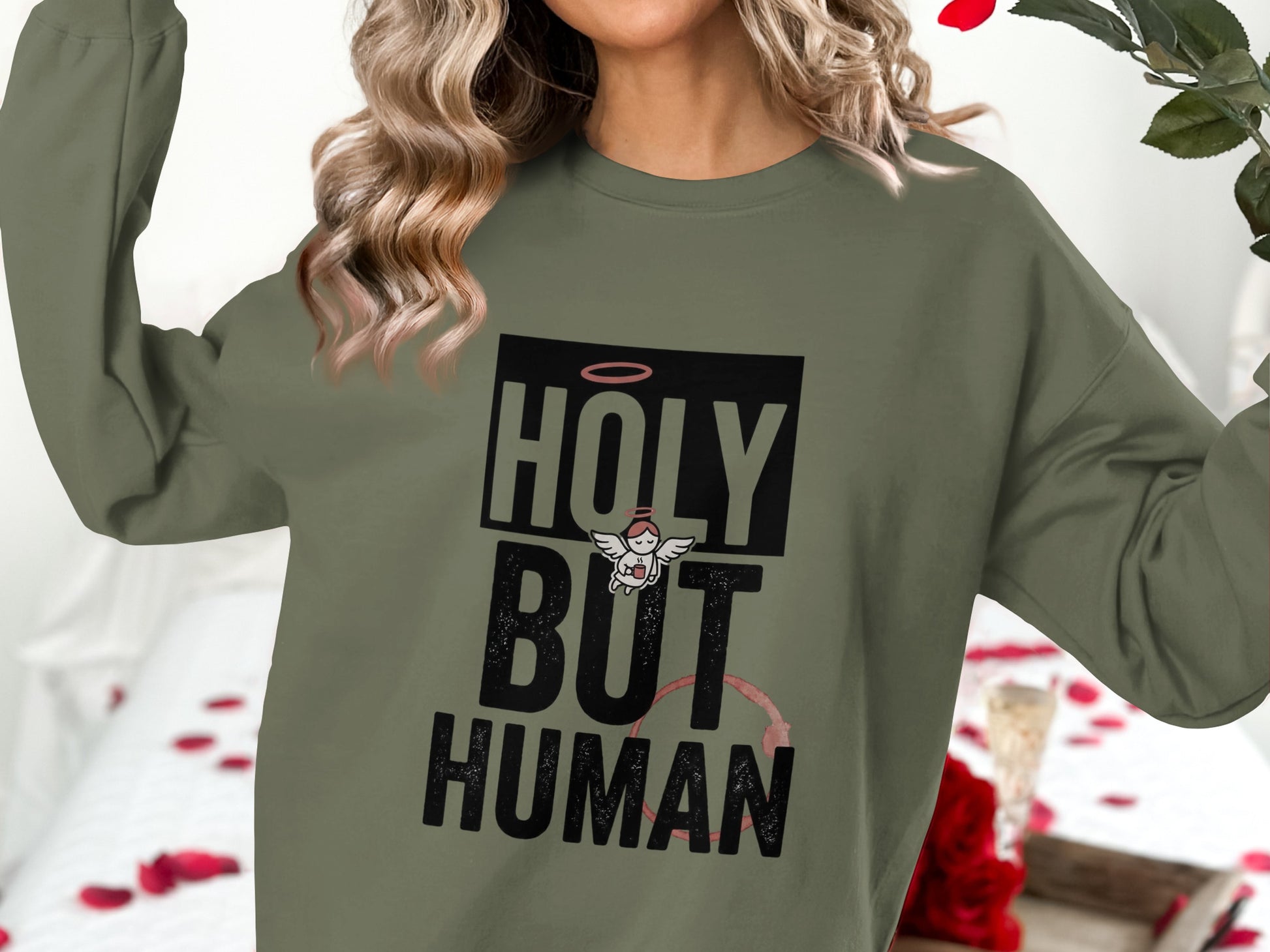 Olive green crewneck sweatshirt with "HOLY BUT HUMAN" text and an angel graphic.