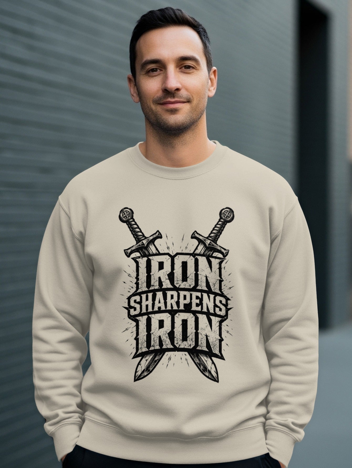 Man wearing a beige sweatshirt with "Iron Sharpens Iron" logo and crossed swords.
