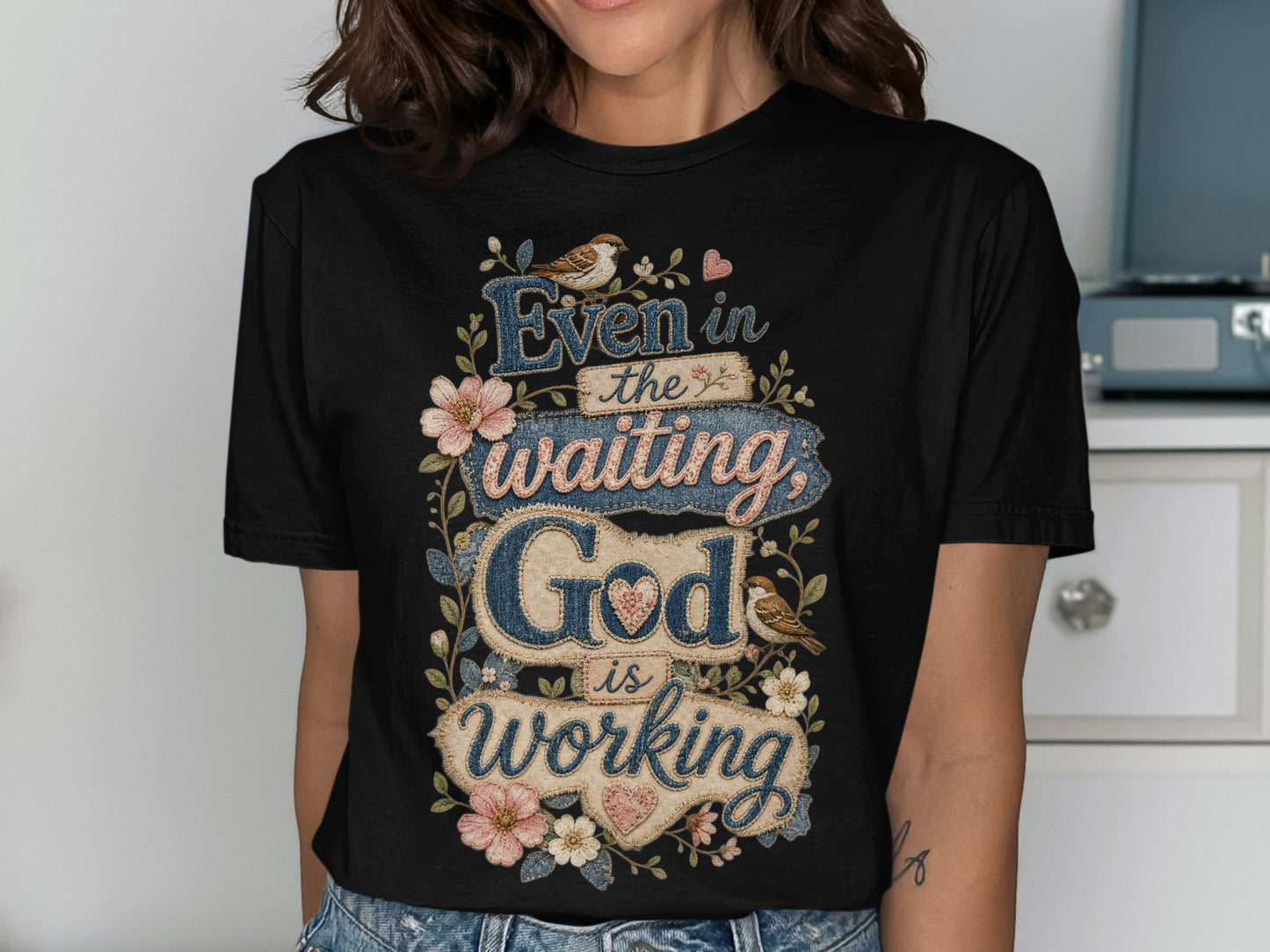 Black t-shirt with "Even in the waiting God is working" text and floral accents.