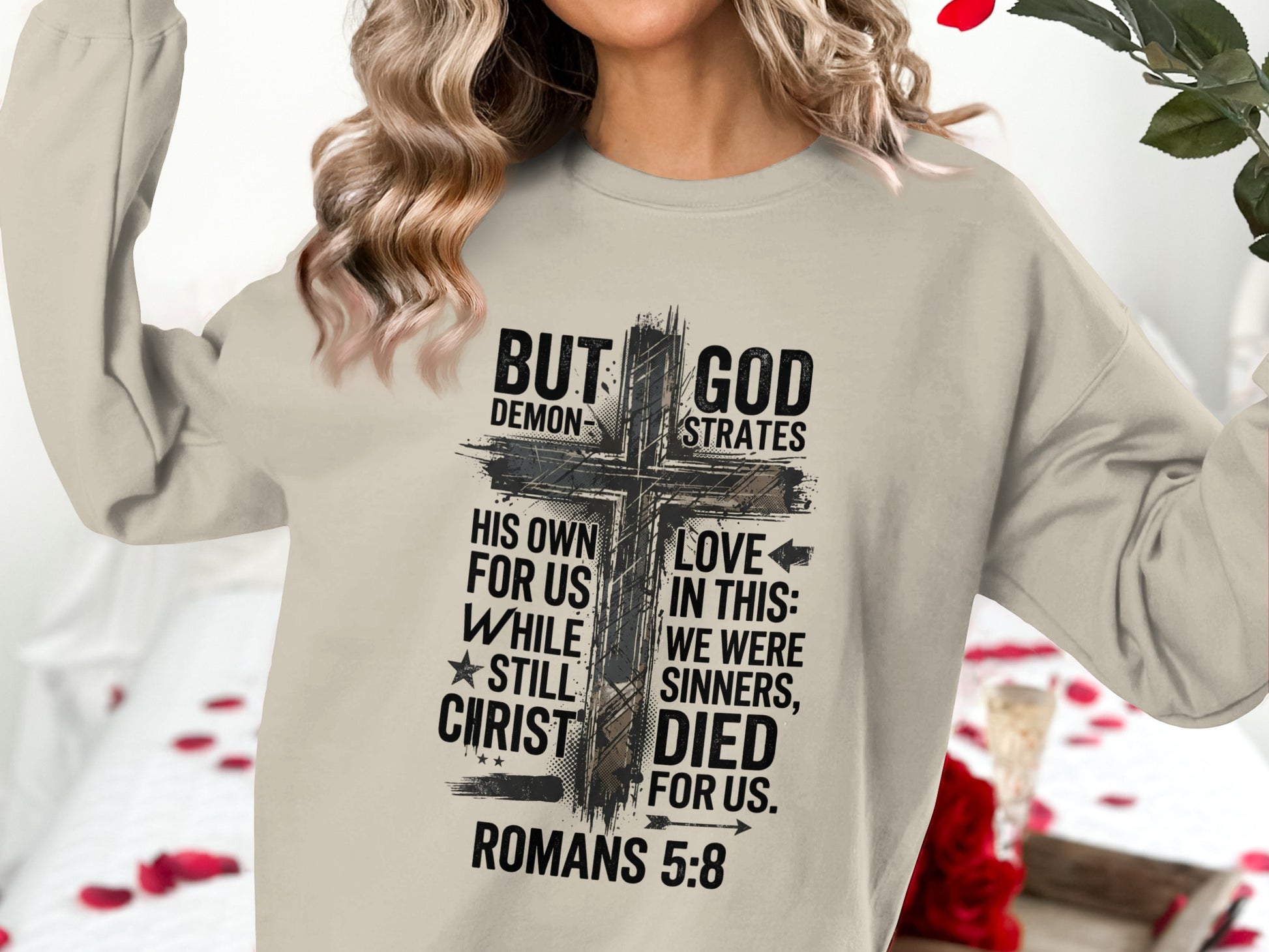 Sweatshirt with "BUT GOD DEMONSTRATES HIS OWN LOVE FOR US WHILE ★STILL WE WERE SINNERS, CHRIST DIED FOR US. ROMANS 5:8" text.