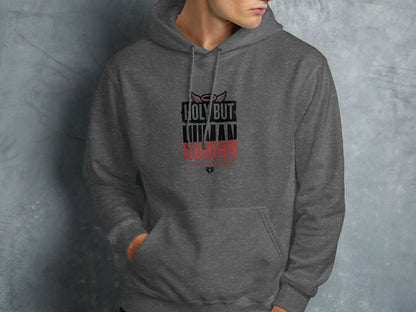 Dark gray hoodie with "HOLY BUT HUMAN" text and angel wings logo.