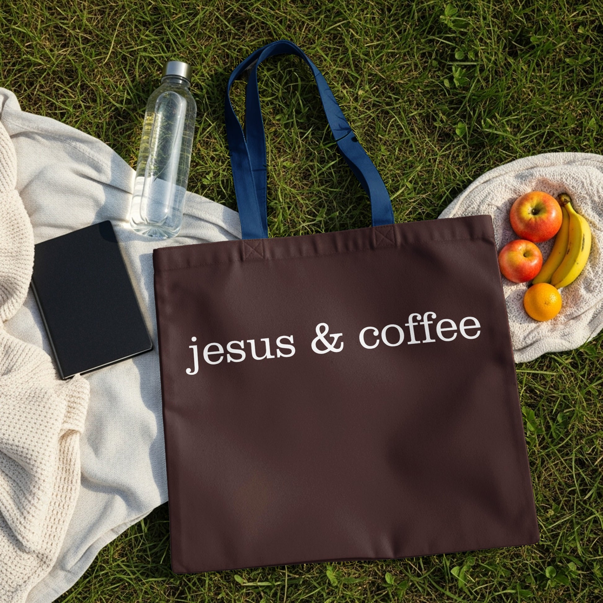 Brown tote bag with white text "jesus & coffee" on grass.