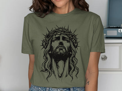 Line art of Jesus with a crown of thorns on a green t-shirt.