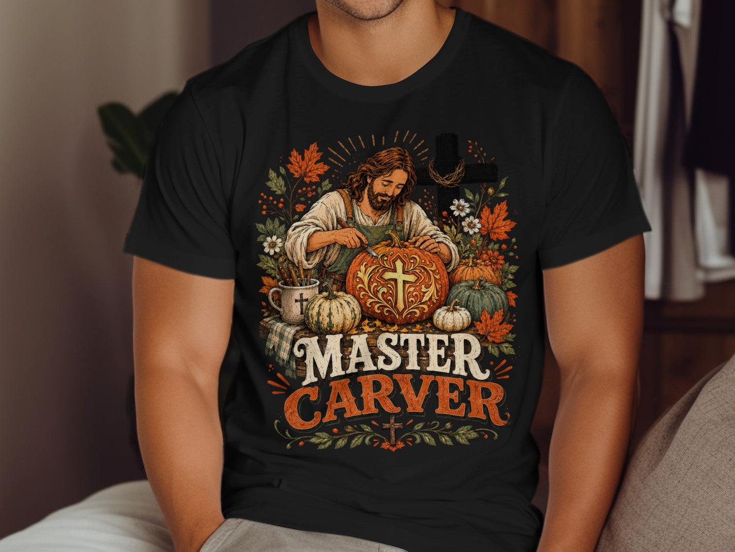 Man in t-shirt carving a pumpkin with autumn leaves and a cross.