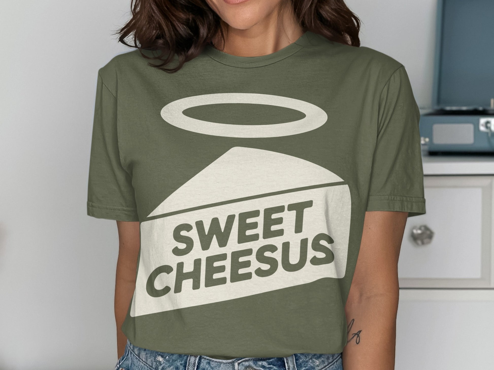 Green t-shirt with "Sweet Cheesus" text and a slice of cheese with halo.