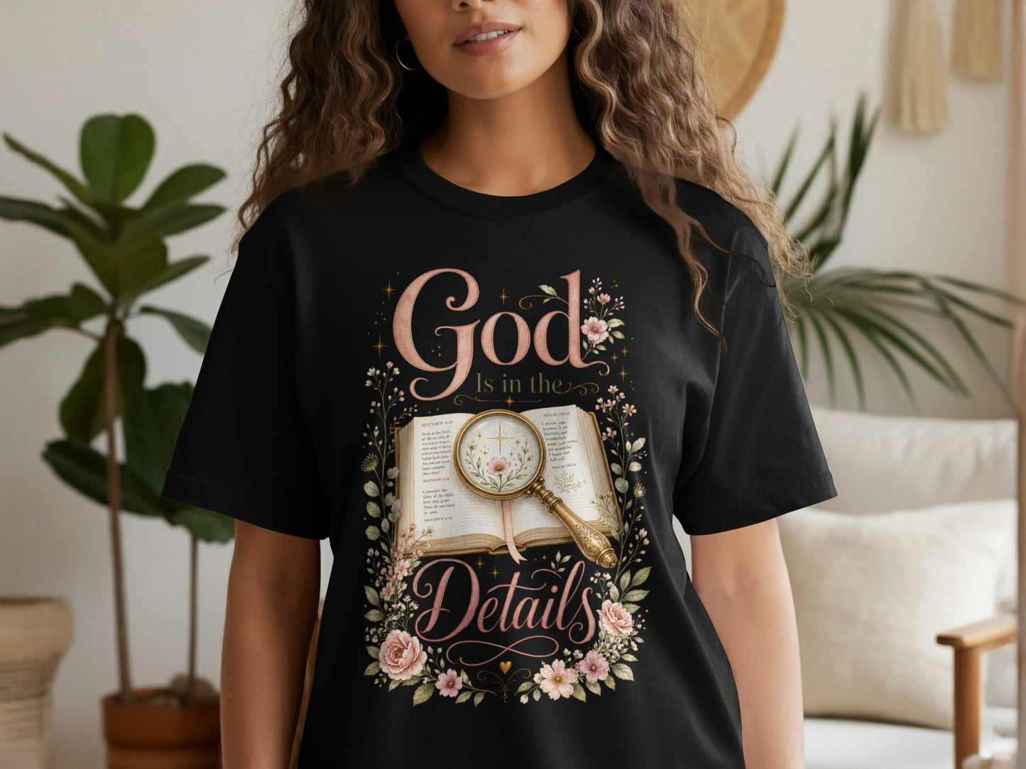 Black t-shirt with "God Is in the Details" text and floral design over open book.