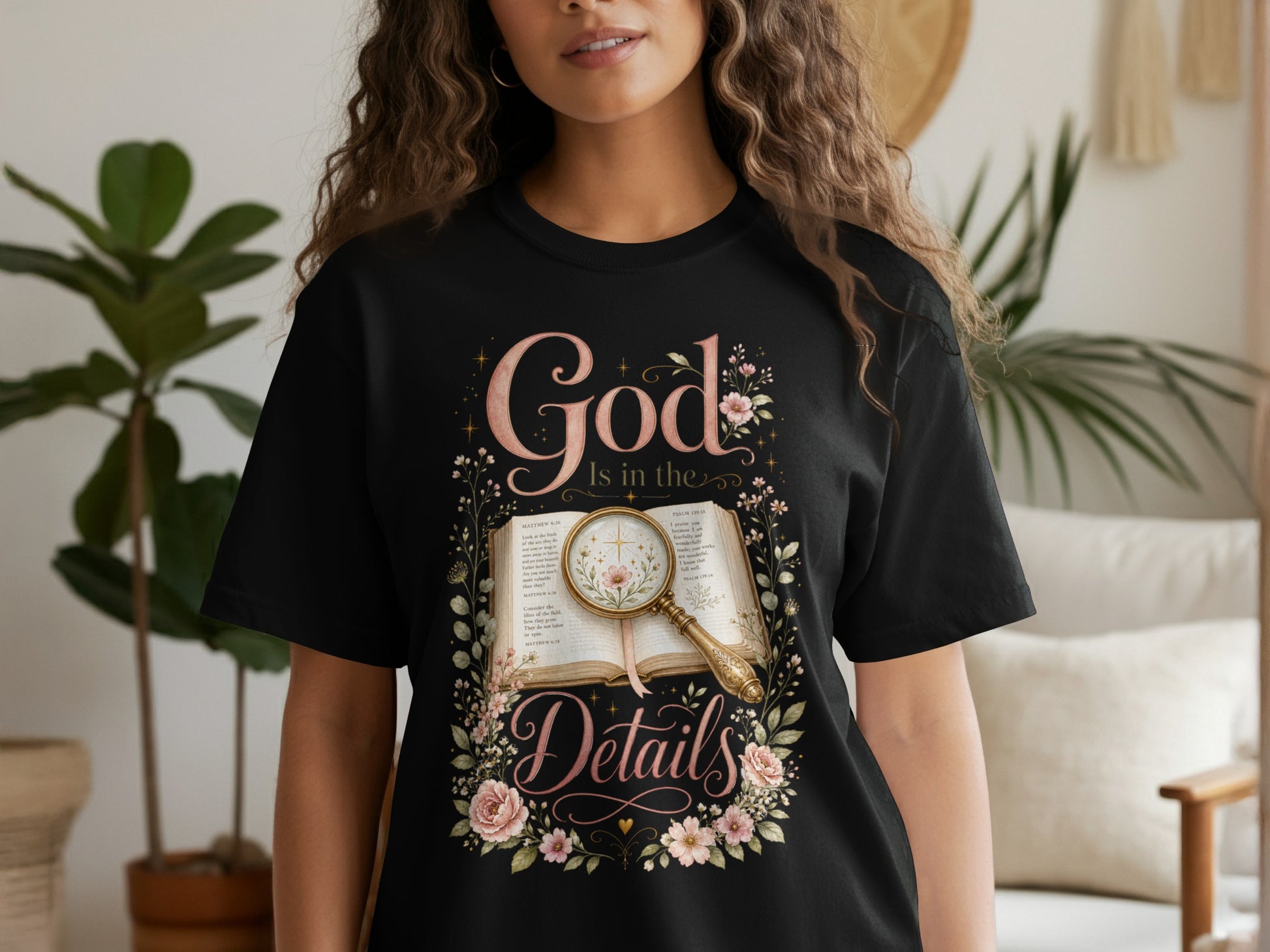 Black t-shirt with "God Is in the Details" text and floral design over open book.