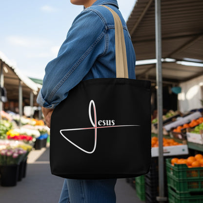 Black tote bag with white and red "Jesus" text and stylized cross design.