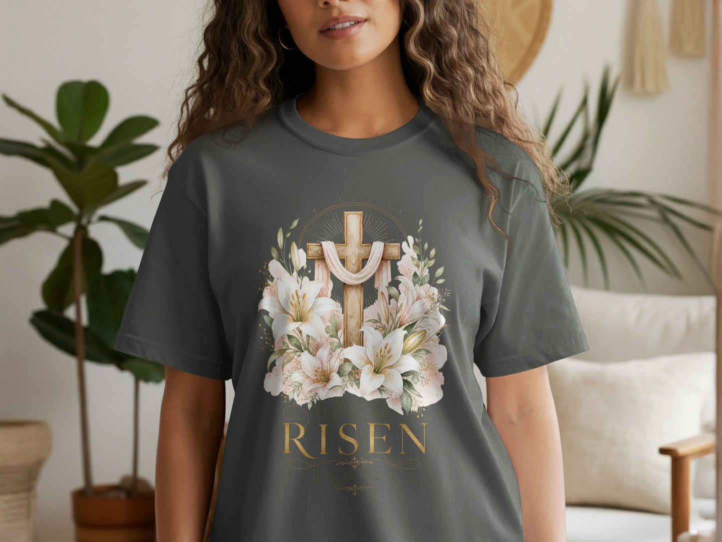 Dark grey t-shirt with a wooden cross, lilies, and gold text "HE IS RISEN".