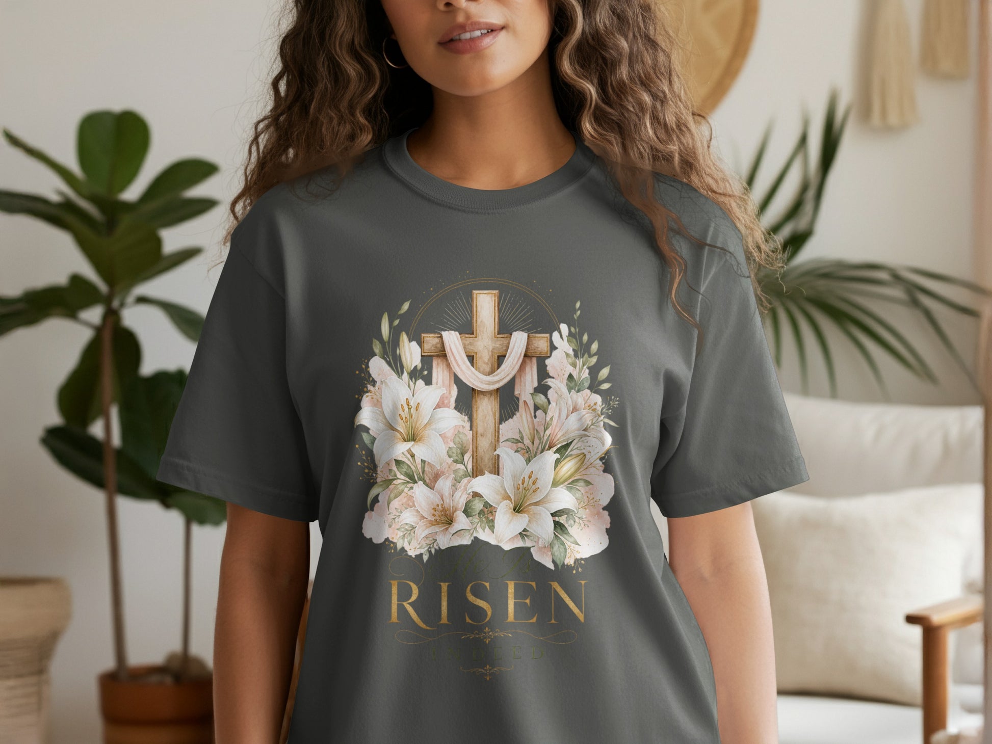Dark grey t-shirt with a wooden cross, lilies, and gold text "HE IS RISEN".
