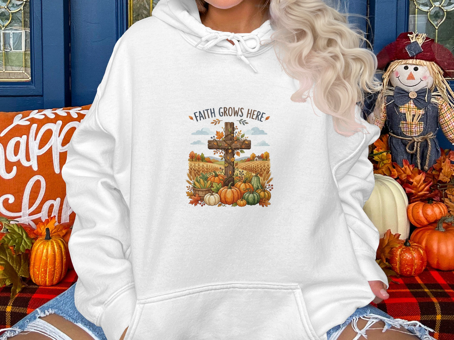 White hoodie with a graphic of a wooden cross surrounded by pumpkins and autumn foliage.