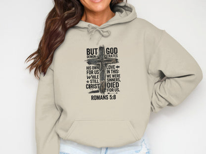 Beige hoodie with cross graphic and "But God" verse from Romans 5:8.