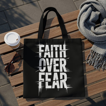 Black tote bag with white "FAITH OVER FEAR" text, laid on a wooden bench.