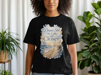 Black t-shirt with a beach sunset graphic and text "Deeper Still, He Calls Me Closer".