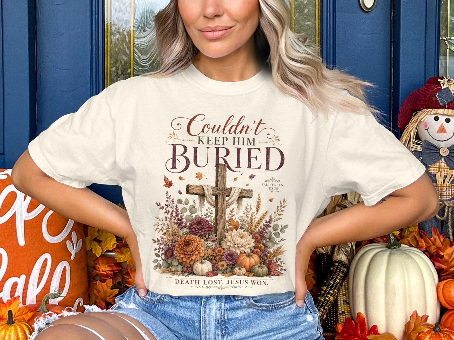 Cream t-shirt with "Couldn't Keep Him Buried" text and a wooden cross with flowers.