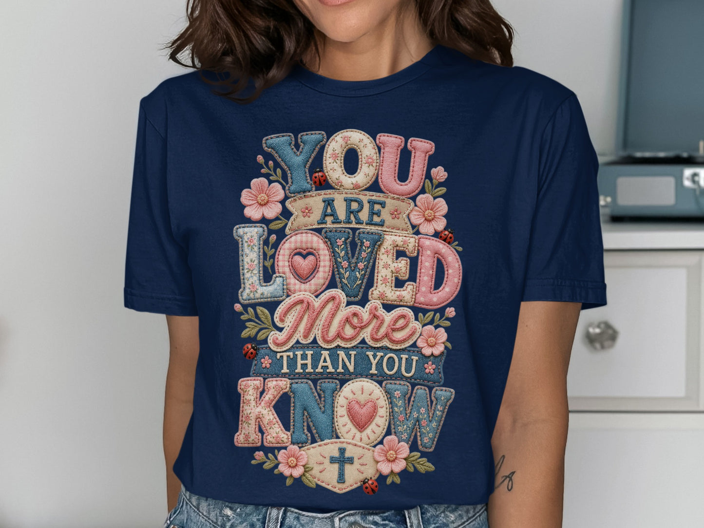Dark blue t-shirt with "YOU ARE LOVED MORE THAN YOU KNOW" text and floral accents.
