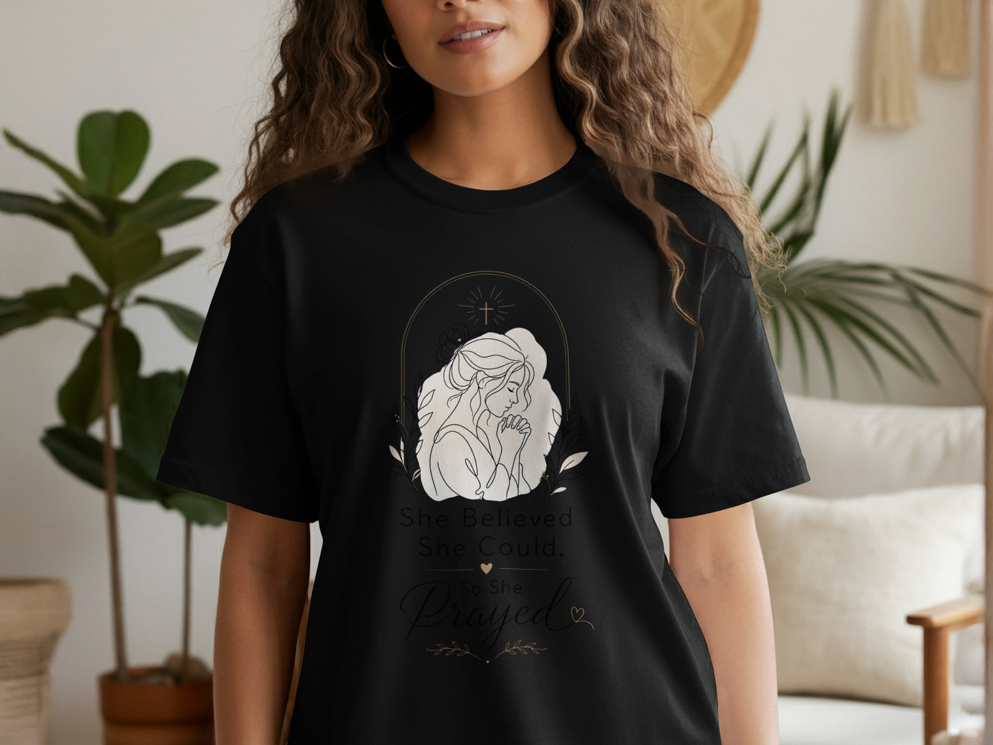 Black t-shirt with line art of a praying woman, cross, and text "She Believed She Could, So She Prayed."