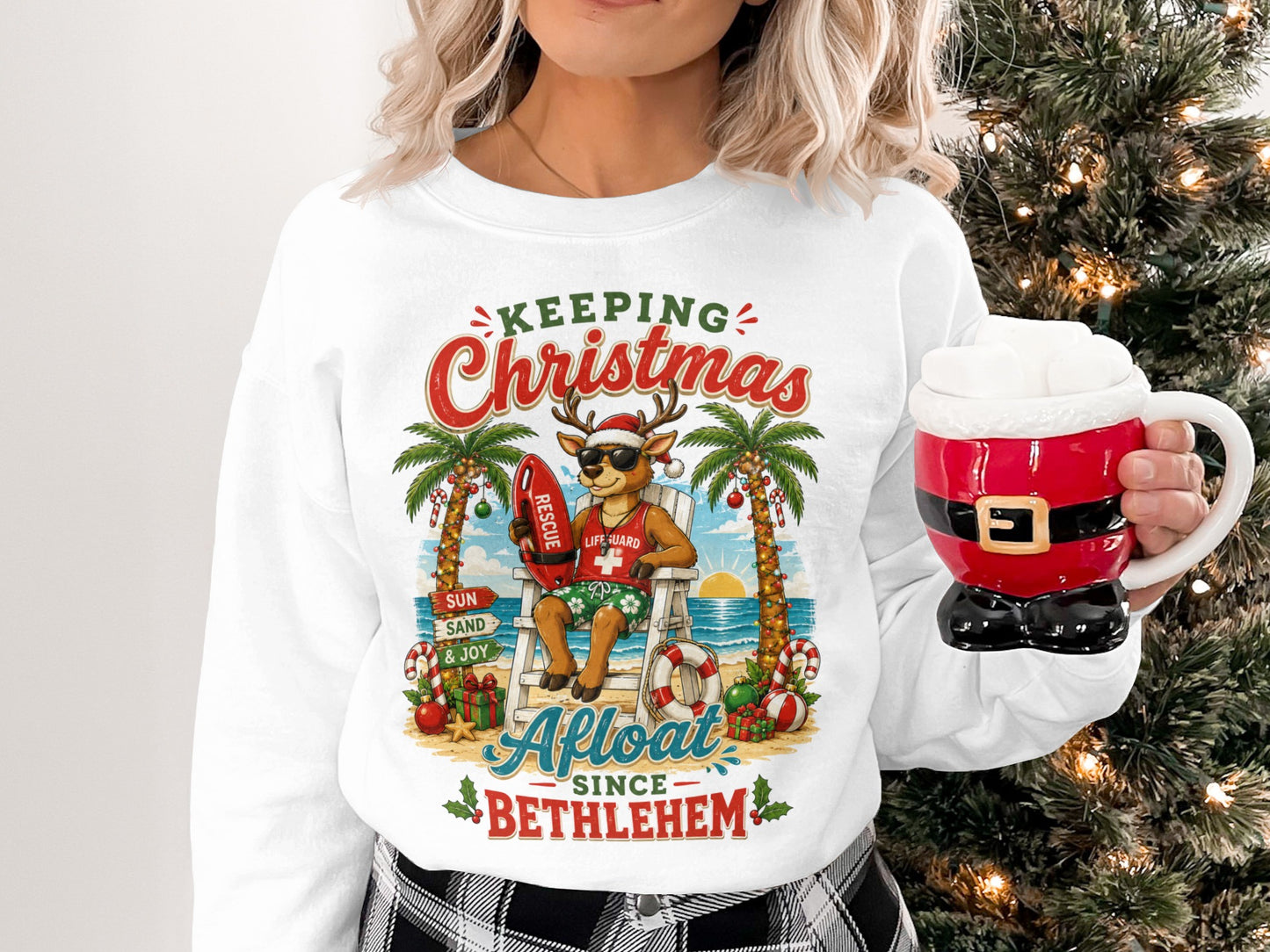 Reindeer lifeguard on beach, wearing sunglasses, holding mug, text reads "Keeping Christmas Since Bethlehem".