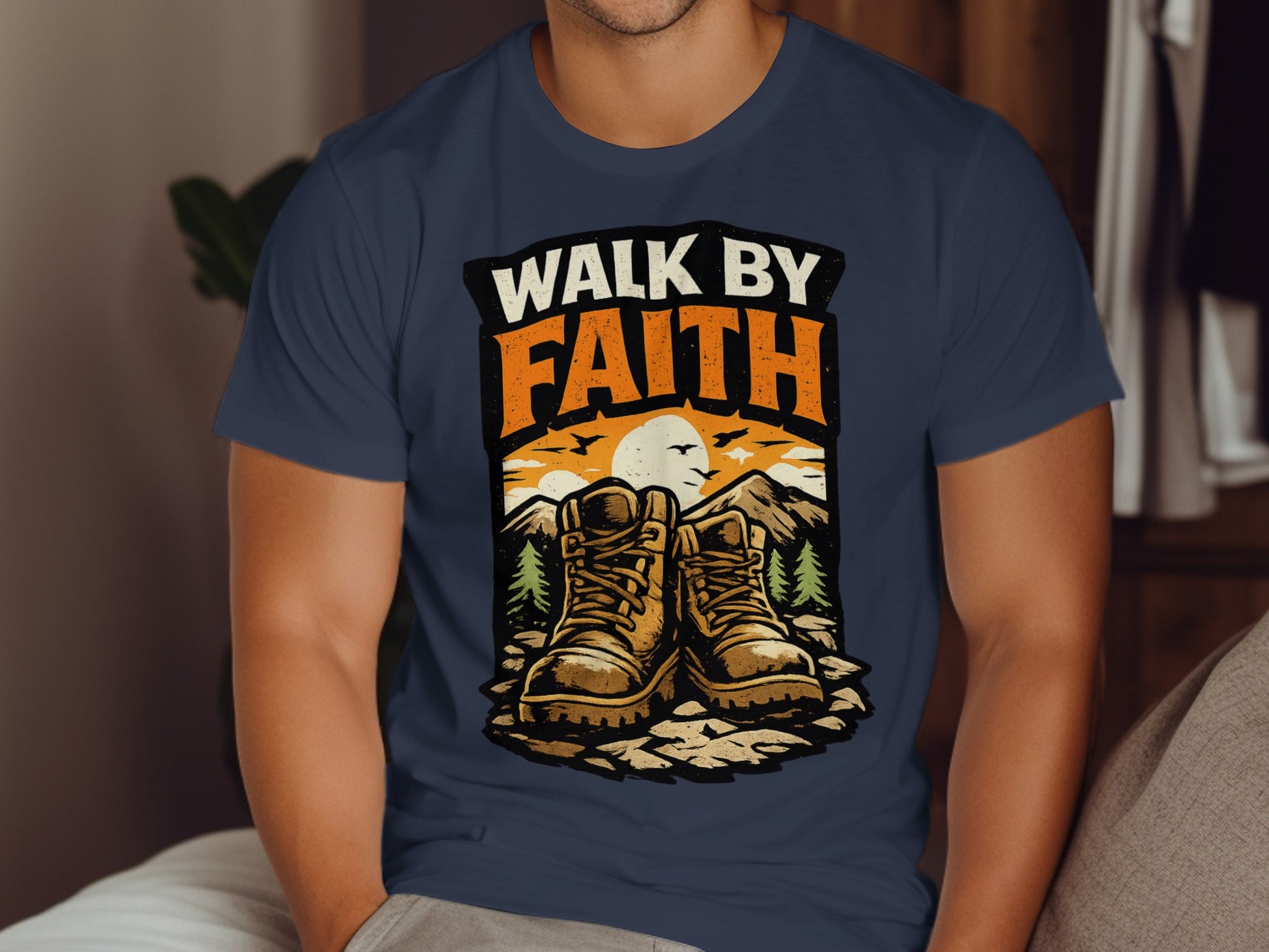 Hiking boots and sunset graphic on a navy t-shirt with "WALK BY FAITH" text.