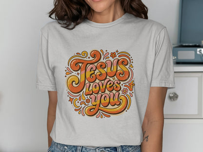 Retro text "Jesus Loves You" with flowers on a light gray t-shirt.
