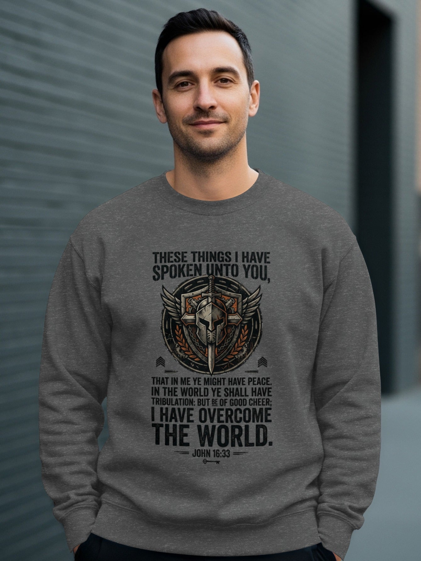 Gray sweatshirt with religious quote and shield design.