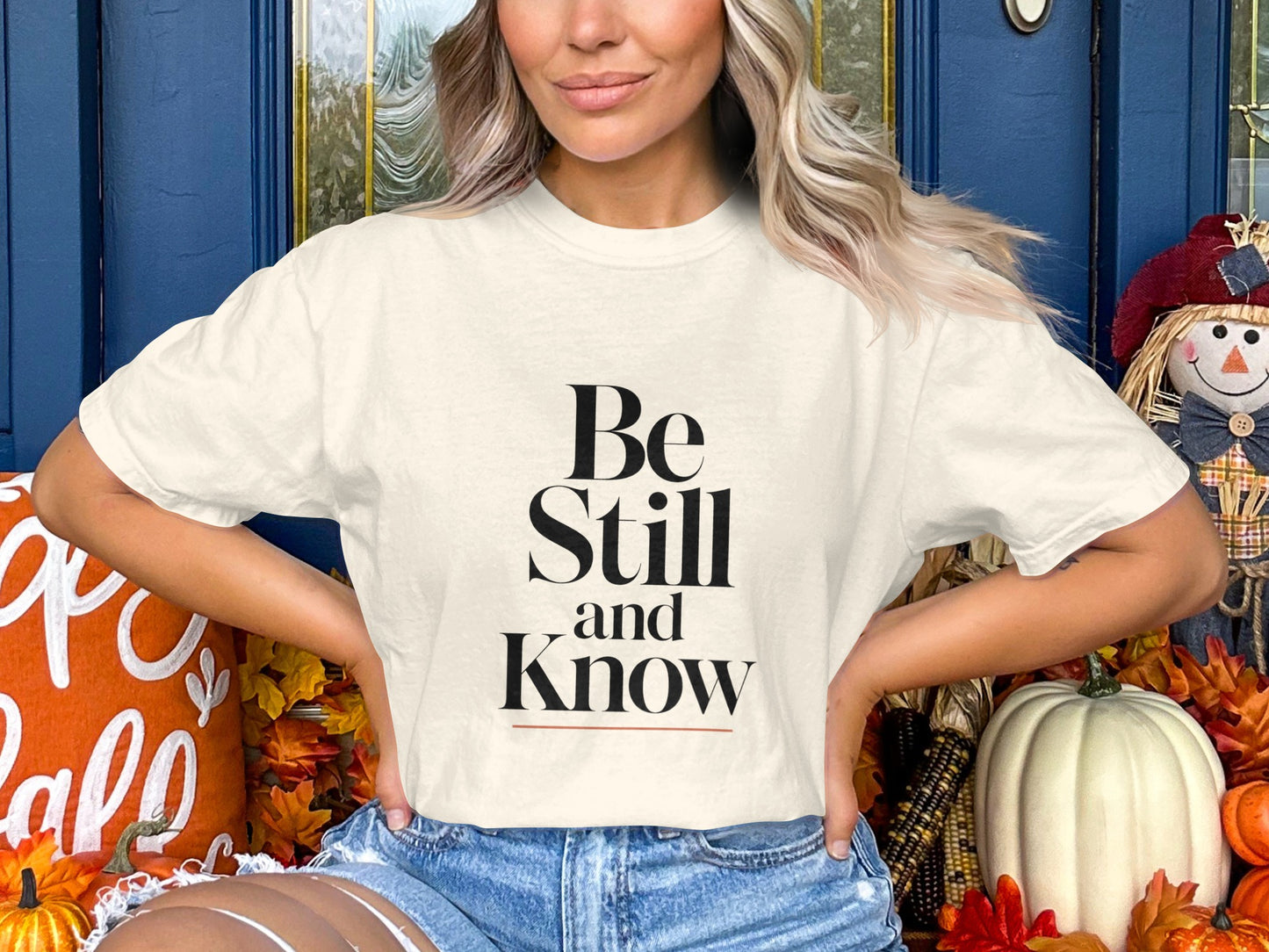 Cream t-shirt with "Be Still and Know" text, worn by a woman.