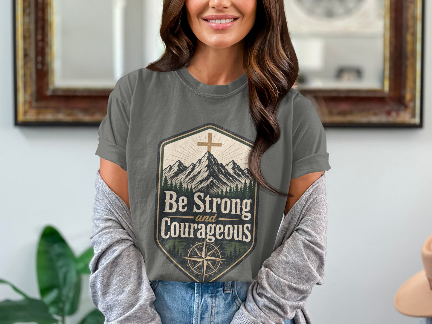 Gray t-shirt with mountains and compass graphic saying "Be Strong and Courageous".