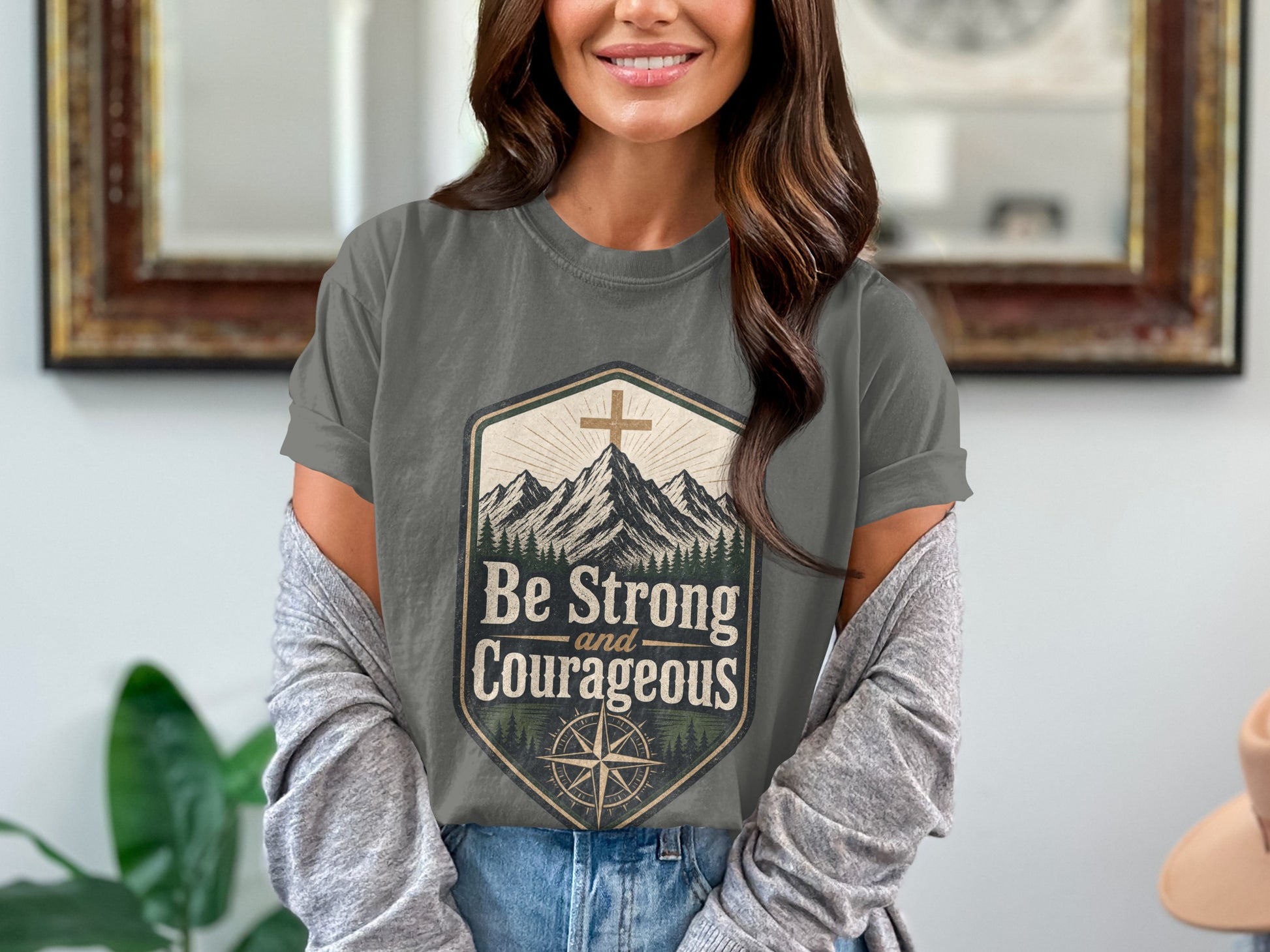 Gray t-shirt with mountains and compass graphic saying "Be Strong and Courageous".