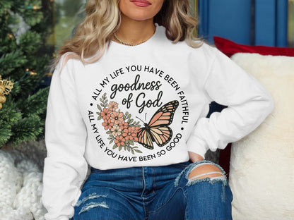 White sweatshirt with "Goodness of God" text and butterfly design.