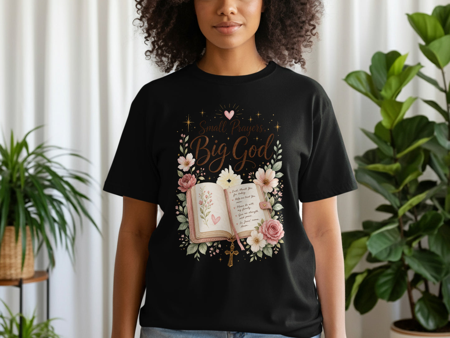Black t-shirt with "Small Prayers, Big God" quote over an open book and flowers.