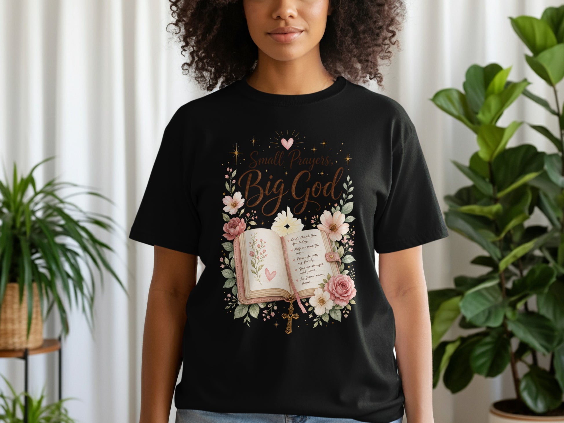 Black t-shirt with "Small Prayers, Big God" quote over an open book and flowers.