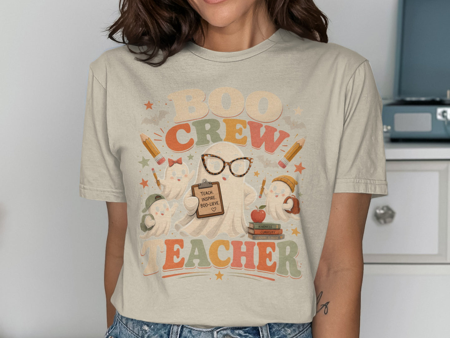 Graphic tee with "Boo Crew Teacher" text and cute ghosts holding school supplies.