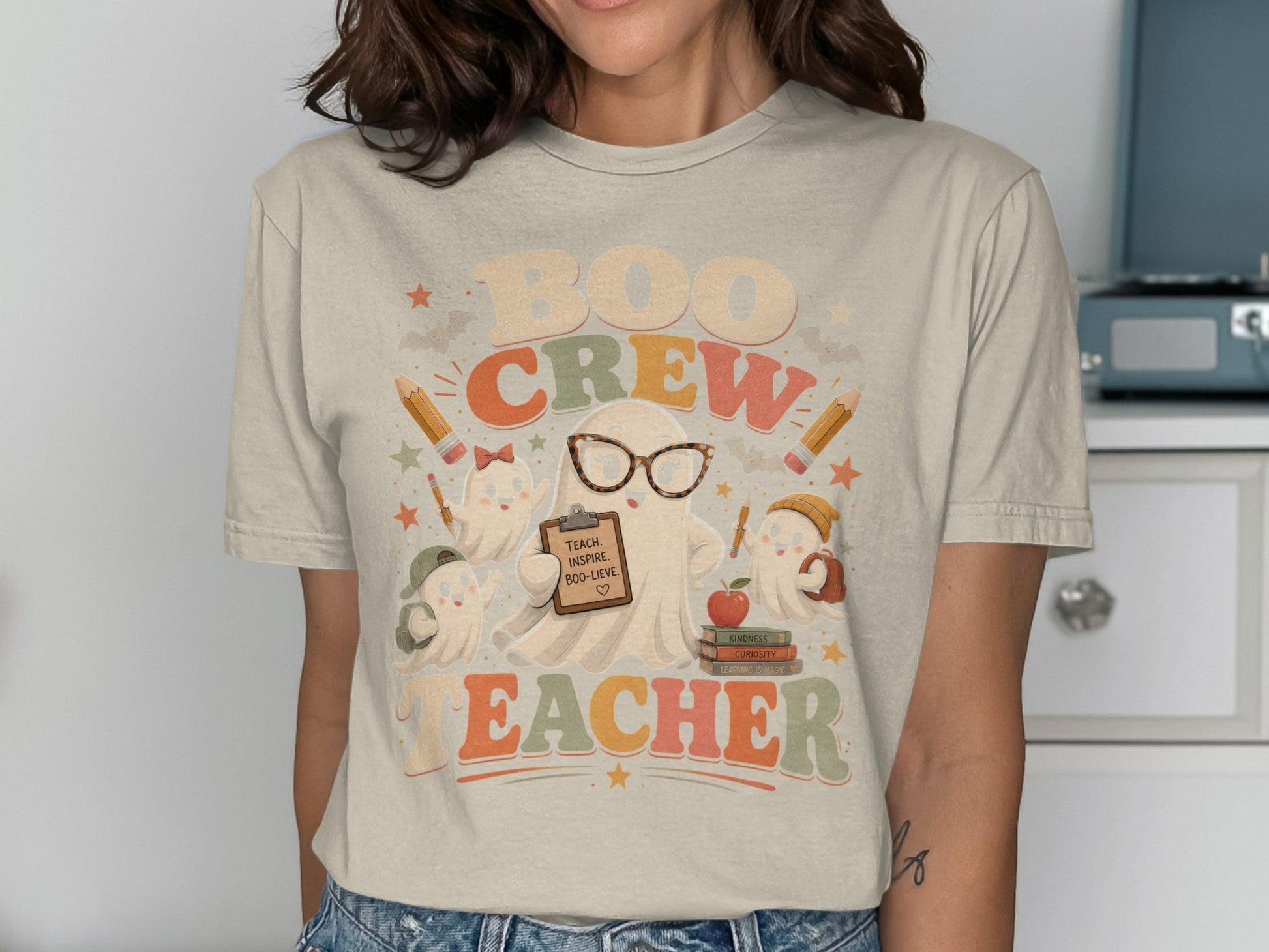 Graphic tee with "Boo Crew Teacher" text and cute ghosts holding school supplies.
