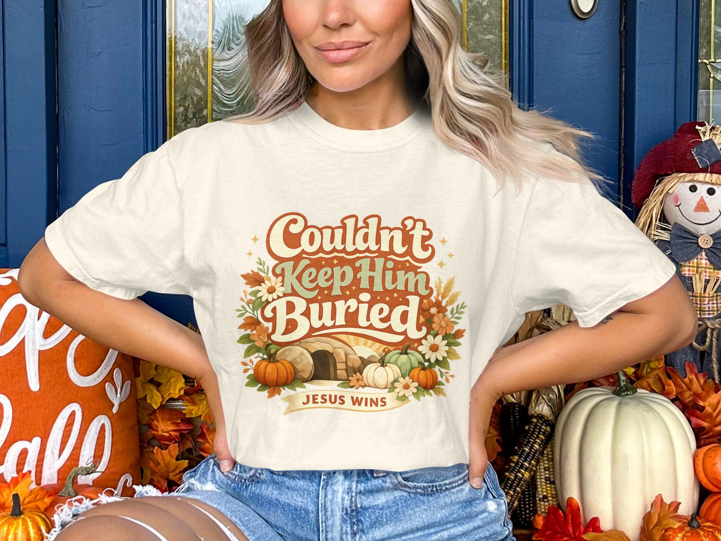 Cream t-shirt graphic with "Couldn't Keep Him Buried" and "Jesus Wins".
