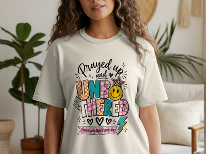 Light cream t-shirt with "Prayed up and UNBOTHERED because God's got it" graphic.