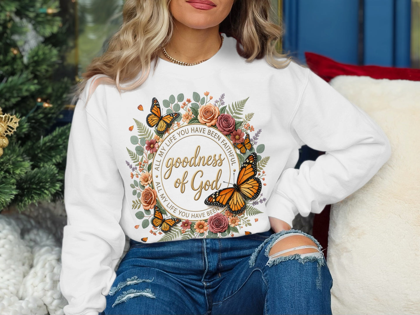 White sweatshirt with floral circle, butterflies, and "Goodness of God" text.