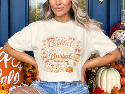 Cream t-shirt with "Couldn't Keep Him Buried He Rose Anyway" text, ghost, and pumpkins.