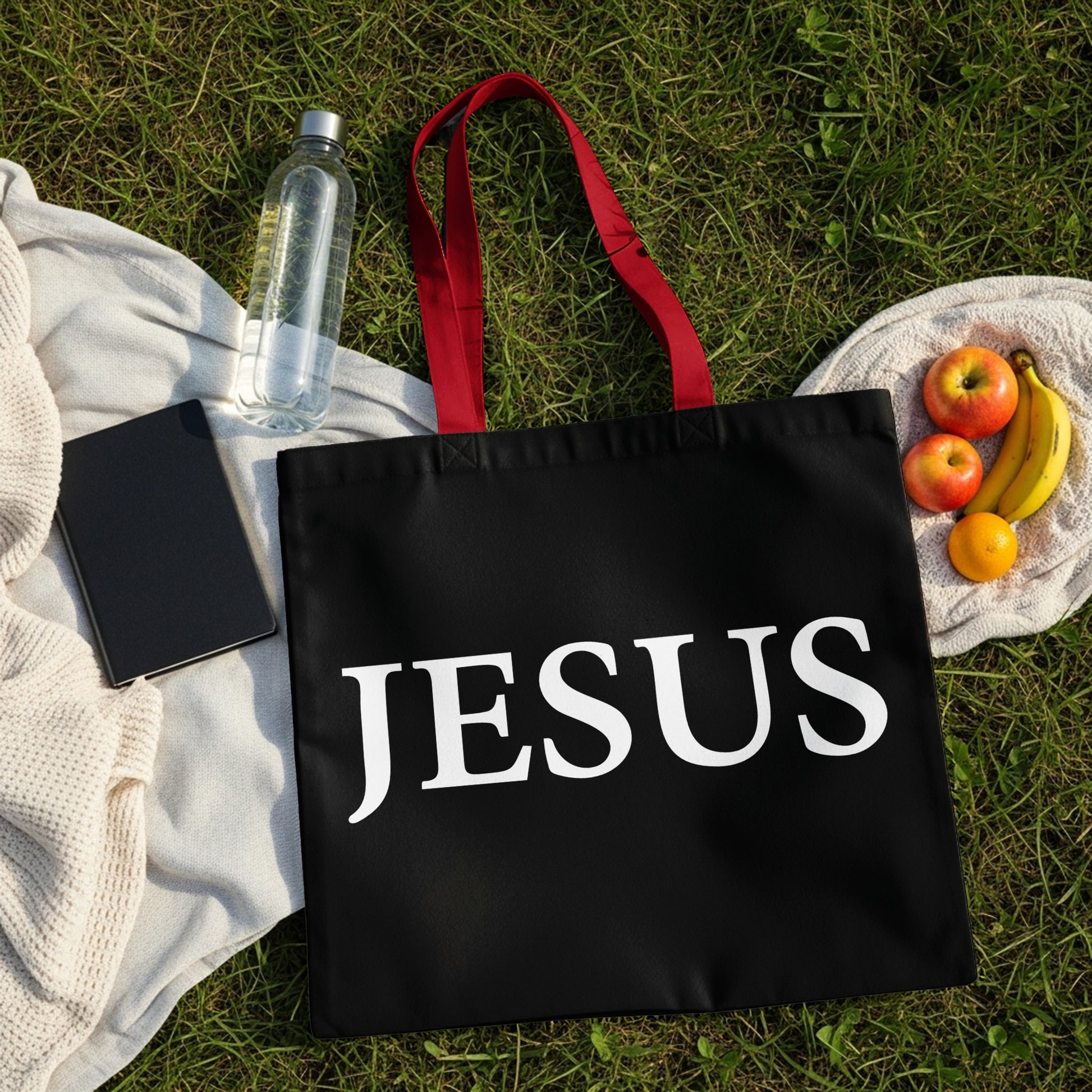 Black tote bag with red handles and "JESUS" in white text.