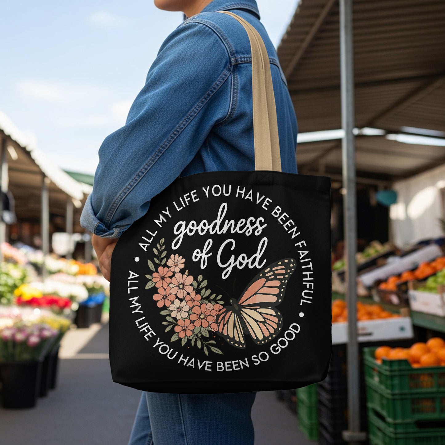 Black tote bag with "goodness of God" text, flowers, and butterfly graphic.