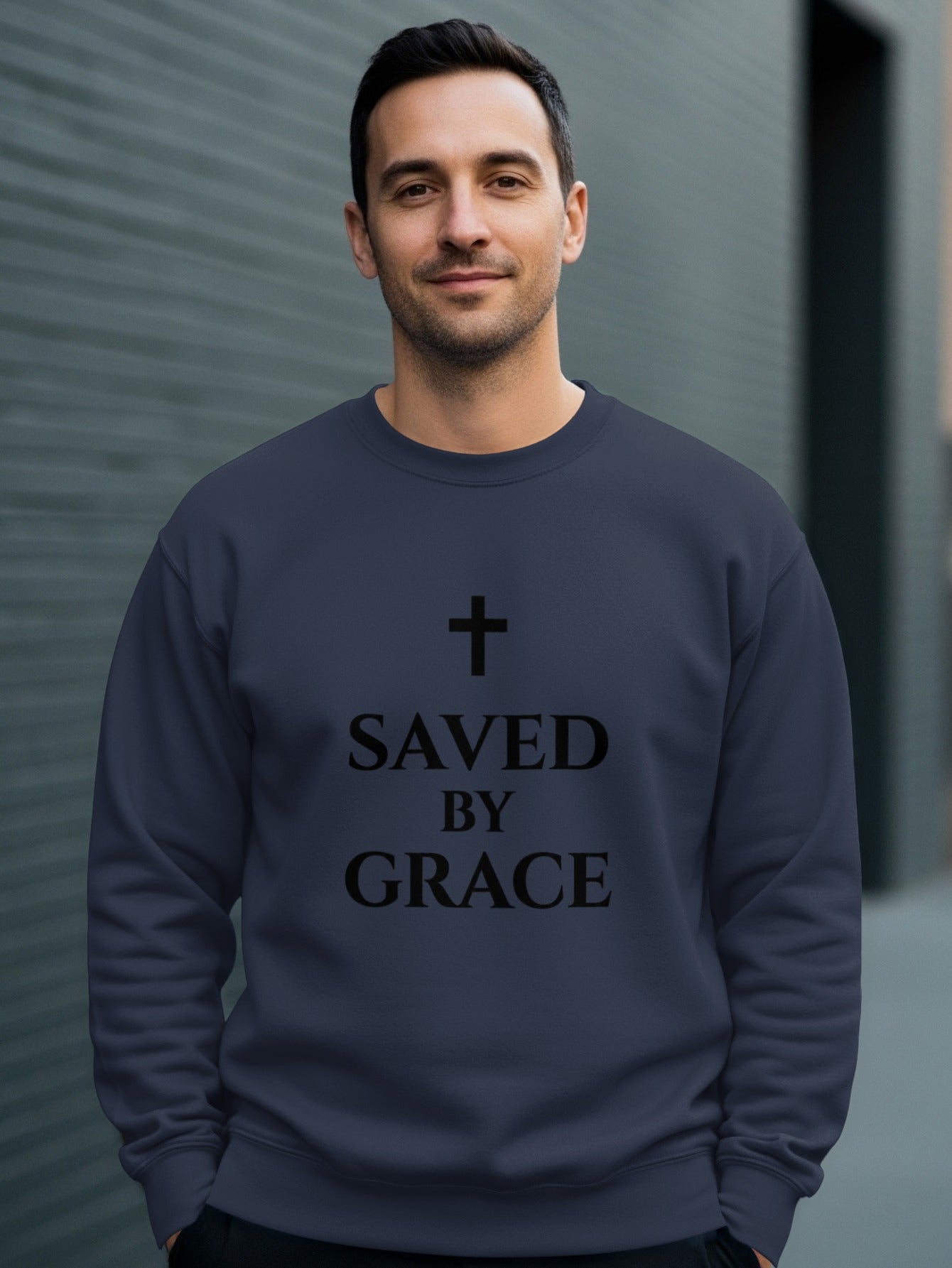 Man wearing a dark navy sweatshirt with "SAVED BY GRACE" and a cross.