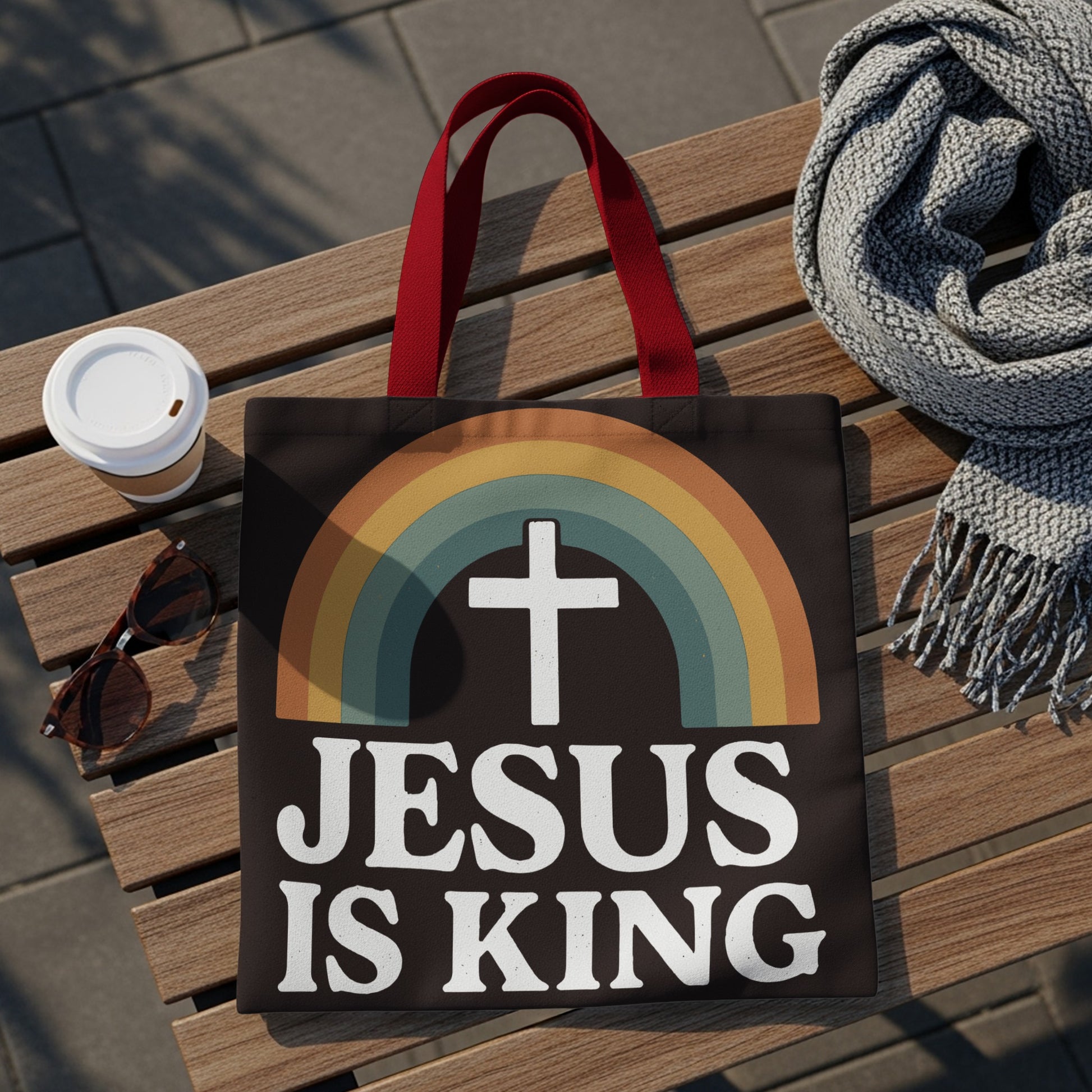 Black tote bag with white text "JESUS IS KING" and a rainbow cross graphic.