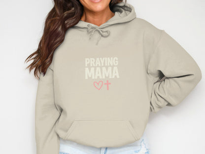 Beige hoodie with "PRAYING MAMA" text and heart and cross graphic.