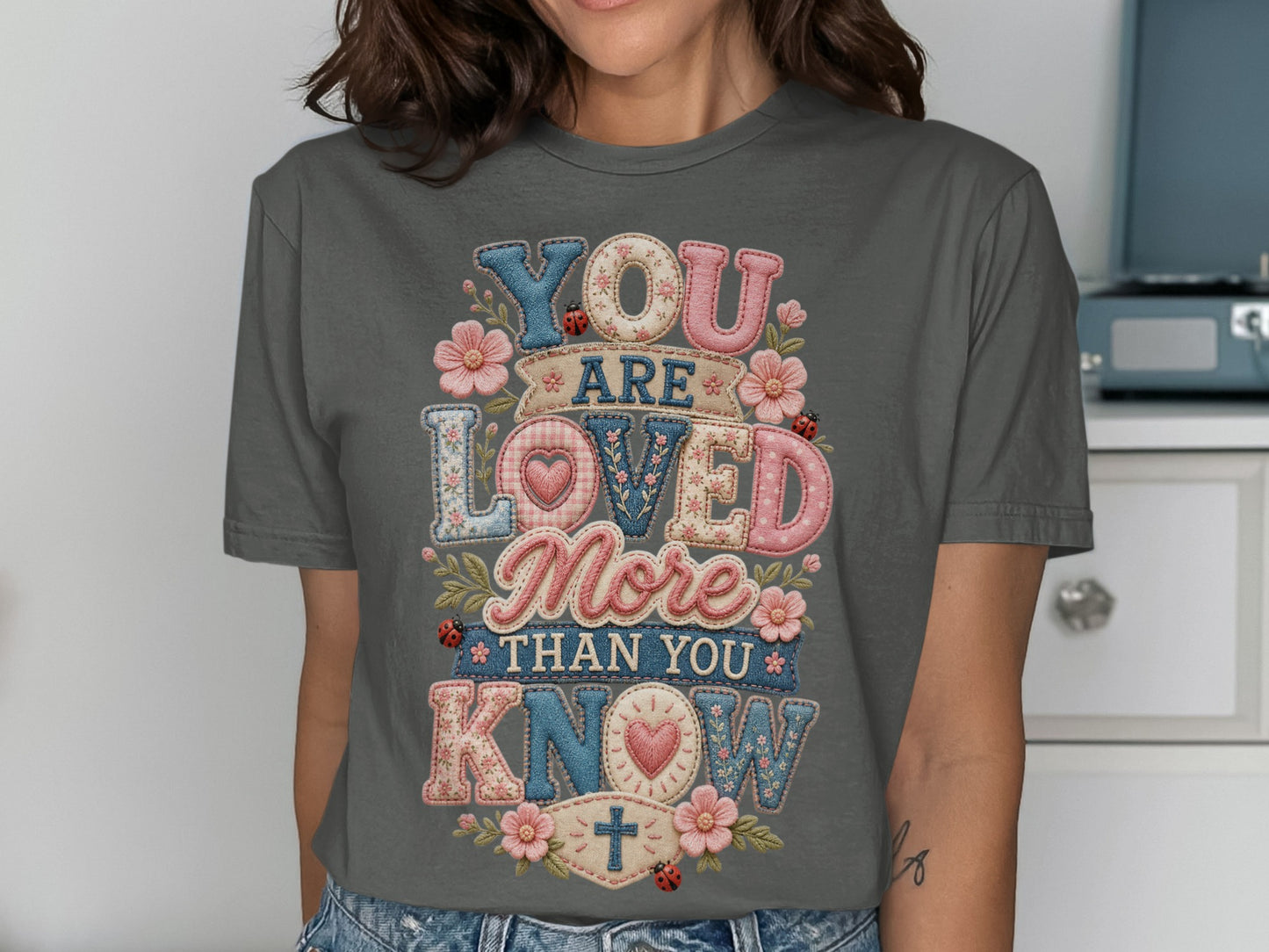 T-shirt with "YOU ARE LOVED MORE THAN YOU KNOW" in patchwork lettering.