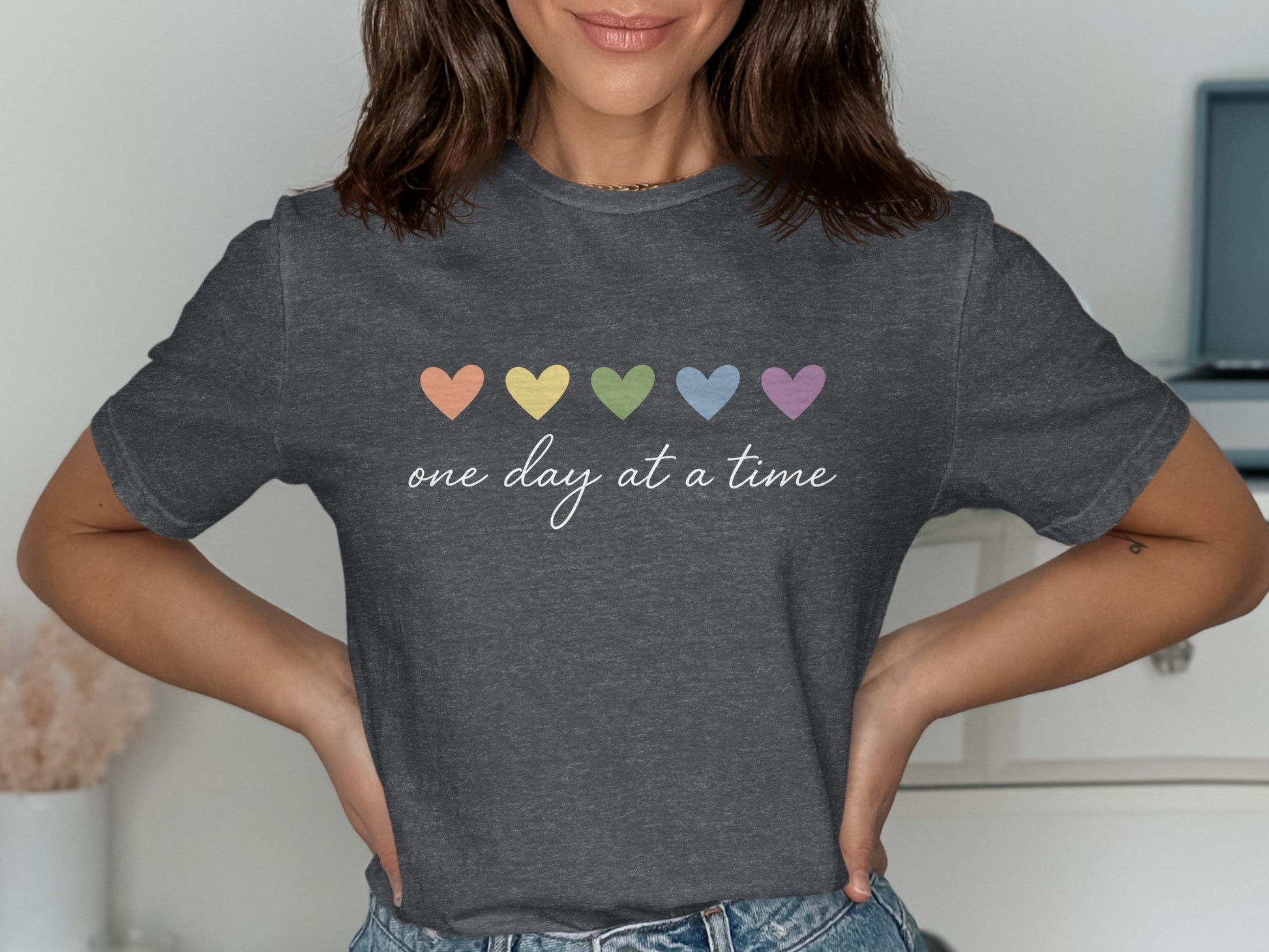 Dark grey t-shirt with rainbow hearts and text "one day at a time".