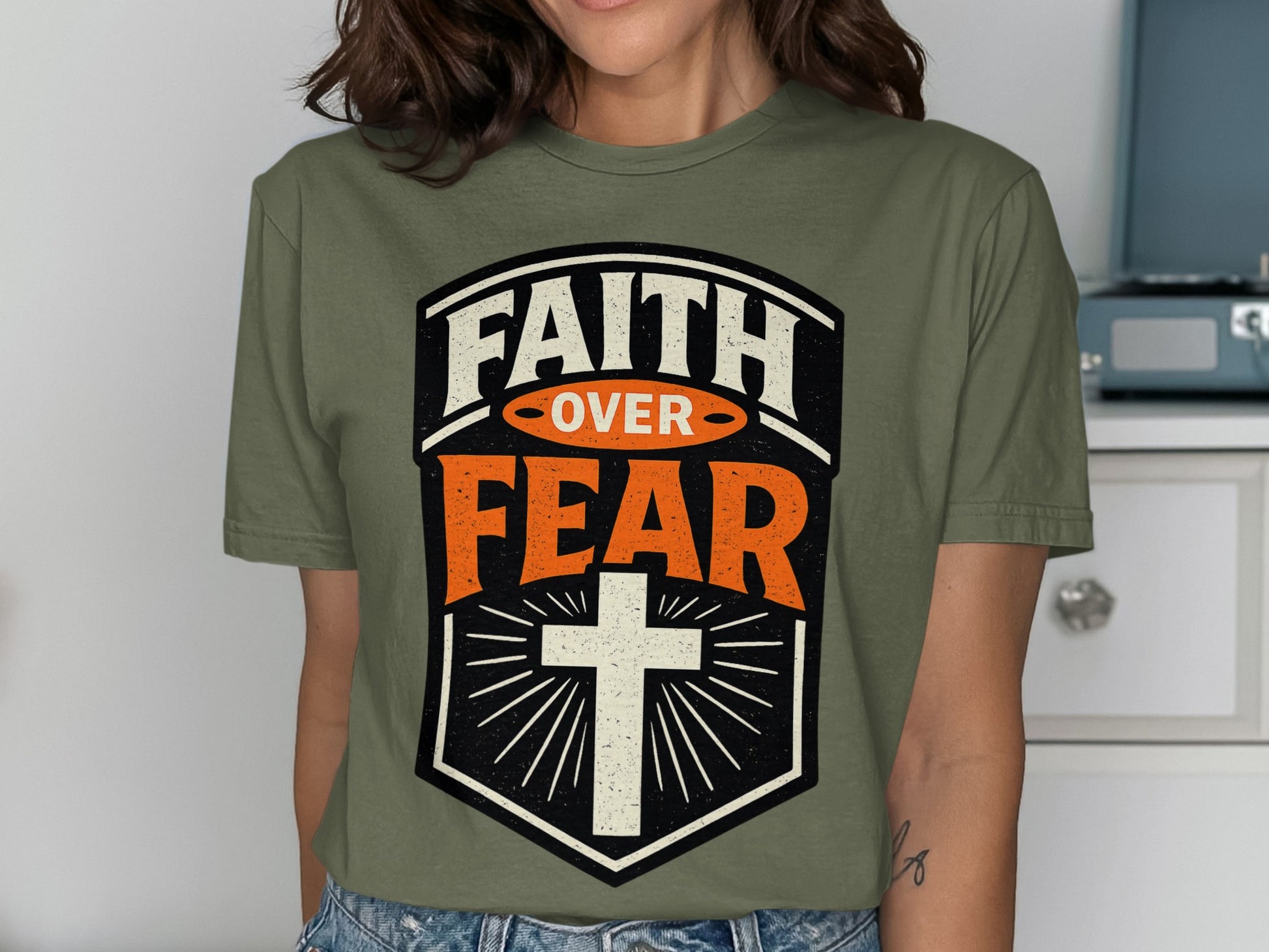 Olive green t-shirt with "FAITH OVER FEAR" text and cross graphic.