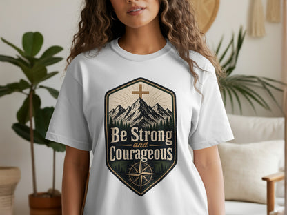 White t-shirt featuring a crest with mountains, a cross, and the text "Be Strong and Courageous".